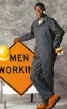 Man wearing coveralls - standing next to a sign reading men working